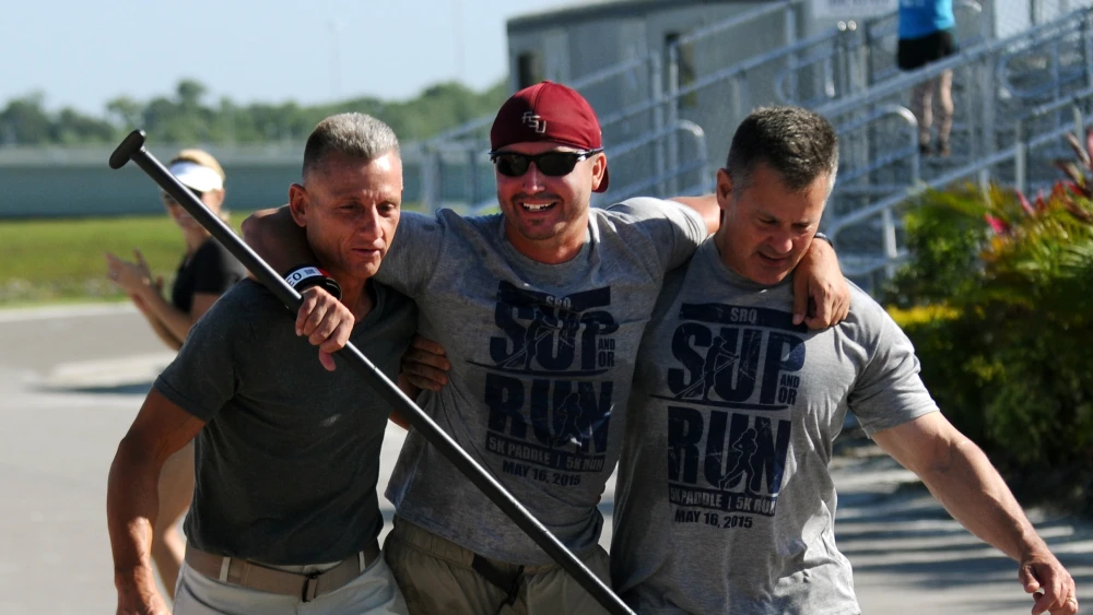 John Helme and Kevin Kenney, volunteers for Operation Second Chance carry Charlie Lemon of Tampa over the finish line at Saturday's first ever SUP & OR RUN (stand-up paddleboard and run event) at Nathan Benderson Park. The event benefits the local chapter of Operation Second Chance, a national organization that supports wounded or ill veterans. May 16, 2015; Herald Tribune/Carla Varisco photo